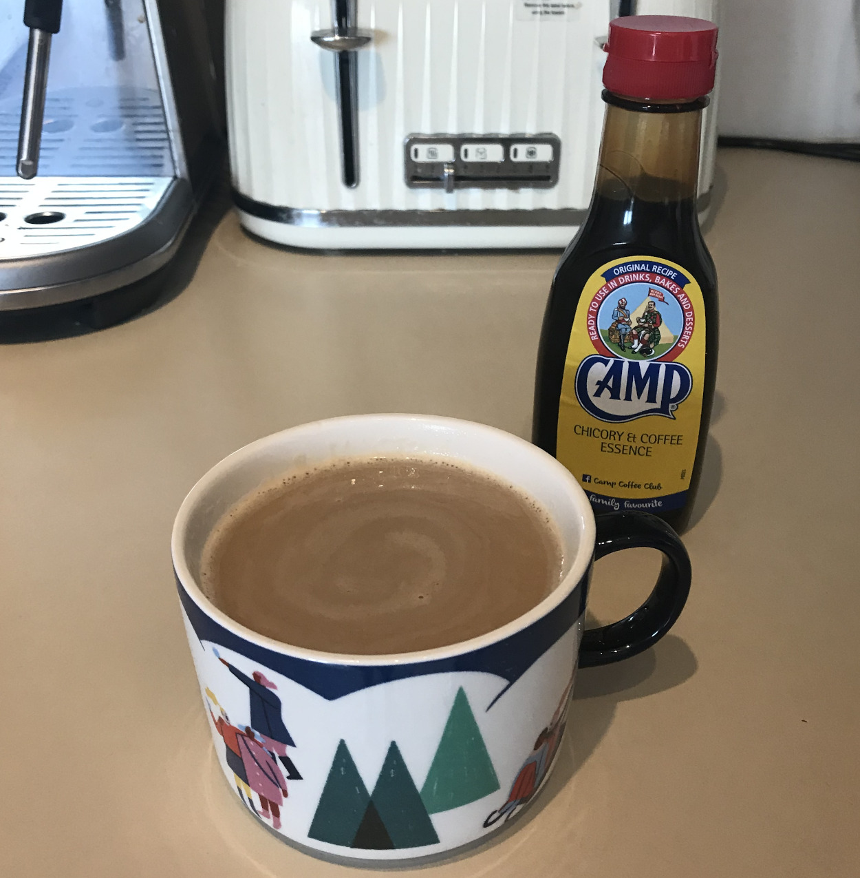 Cup of coffee next to a bottle of Camp Coffee Chicory Essence